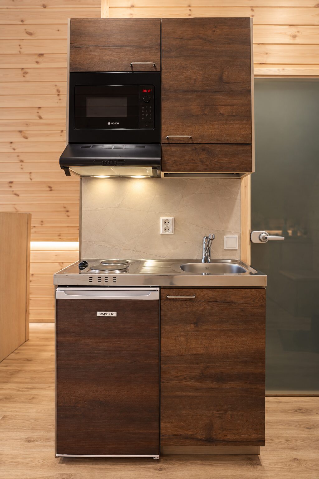 Küchenzeile der Hütte mit zwei Kochplatten, Spüle, Kühlschrank und Mikrowelle