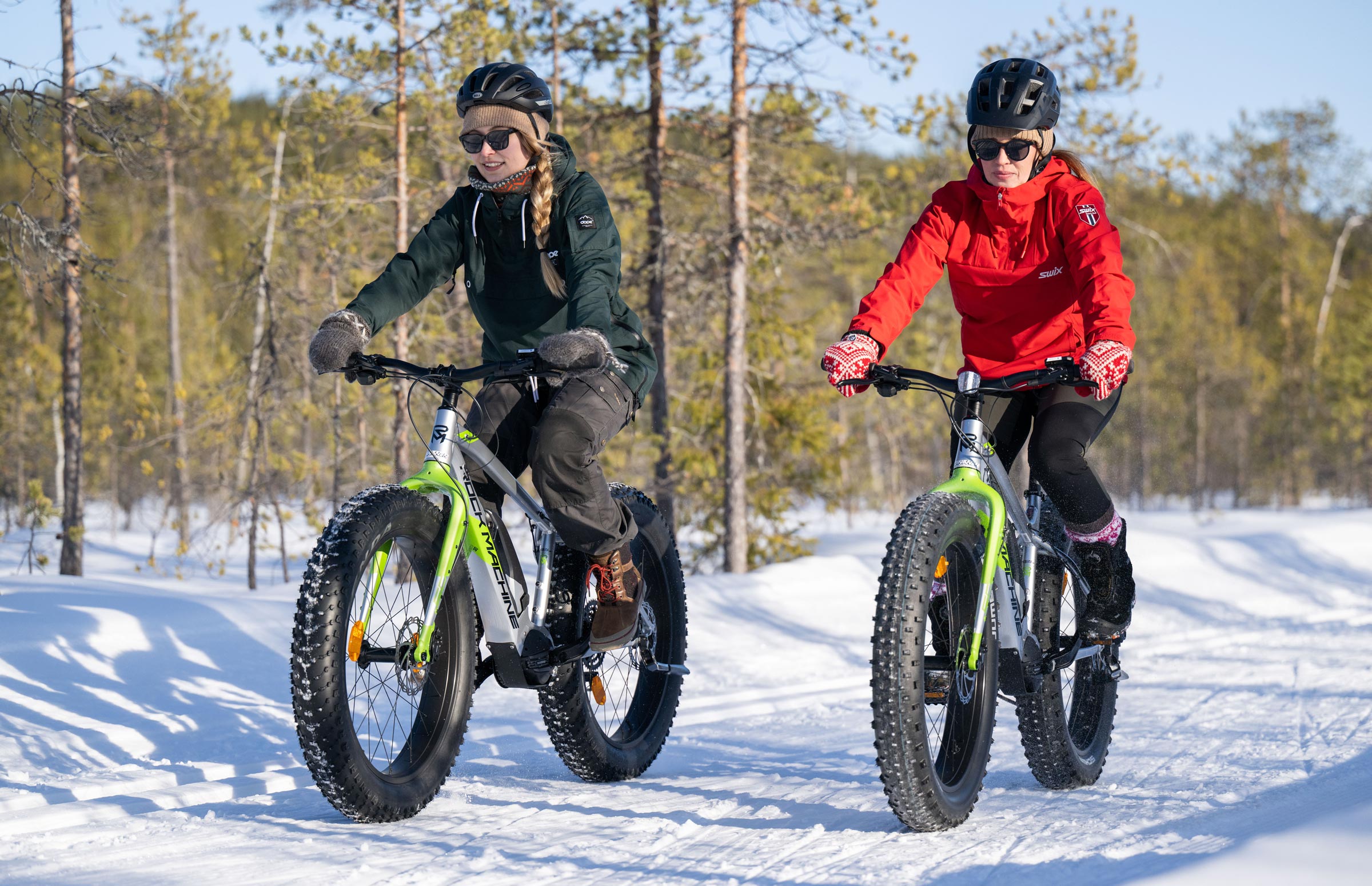 Radfahrerinnen auf E-Mountainbikes auf einer verschneiten Route in Suomu